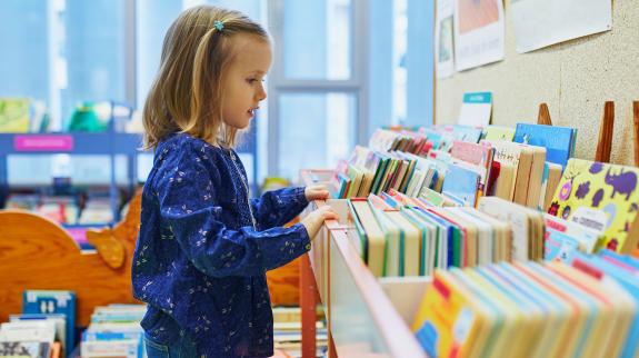 Child explores a box filled with books.