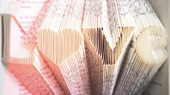 The word "Love" with a pink gradient folded into the pages of an old book.