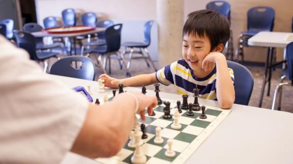 A young boy and an adult engaged in a friendly game of chess, focused on their strategy and moves.