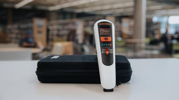 A thermal leak detector placed on a table in a library, showcasing its use for measuring surface temperatures.