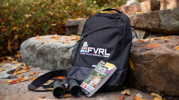 A travel backpack featuring, binoculars, and a map, perfect for exploring nature.