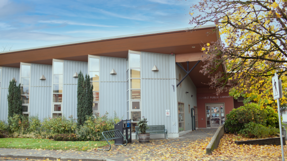 Exterior view of Agassiz Library featuring a tree adorned with bright yellow leaves, highlighting the essence of fall.