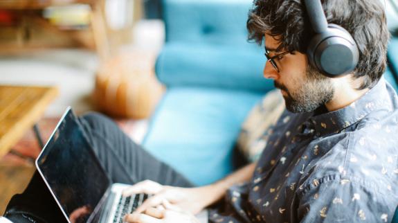 A man with headphones sits on a couch, engaged in learning with Mango Languages.