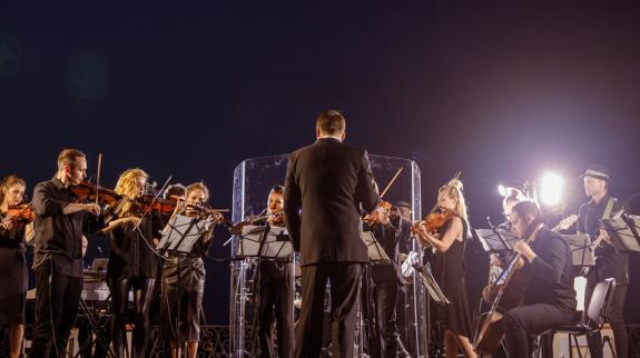 Musicians playing on stage at night, illuminated by stage lights, showcasing their talent in a lively music setting.