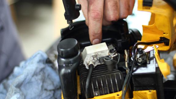 A person works diligently on a small engine, showcasing their skills in a garage setting.