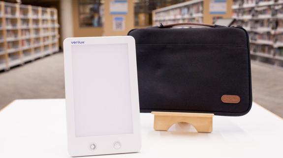 A sunshine lamp rests on a table beside a sleek black bag, showcasing a modern workspace setup.