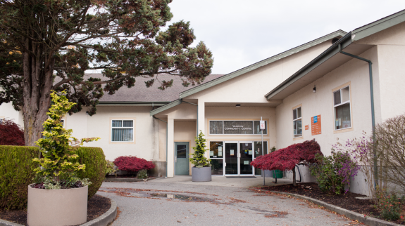 The exterior of Yarrow Library features a large tree prominently positioned in front of the building.