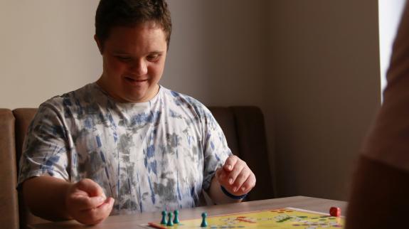 A man and his friend enjoy a lively board game, sharing laughs over the game board.