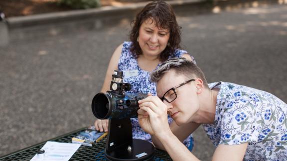A man and woman gazing through a telescope, sharing a moment of wonder under the sky.