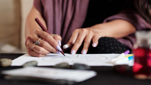 Close up of woman's hands, with purple painted fingernails, as she practices line drawing