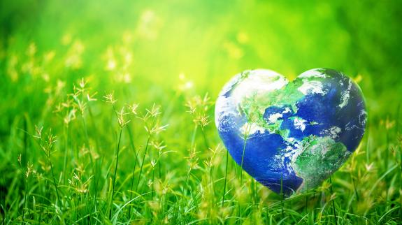 Earth in heart shape on green grass on sunlight - Earth Day concept. Elements of this image furnished by NASA.