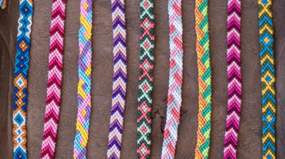 Colourful embroidery floss bracelets on brown table.