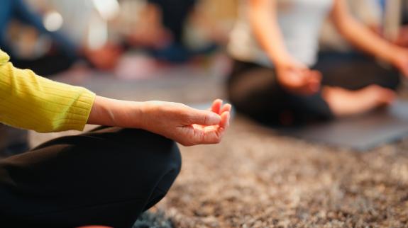 A woman practicing breathing and meditation, seated with hands raised, reflecting calmness and concentration in a tranquil atmosphere.