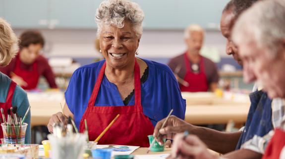 Senior citizens engaged in painting activities at a library program, showcasing creativity and social interaction.