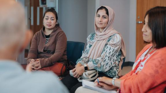 A group of women engaged in conversation while sitting in a circle, fostering a sense of community and connection.