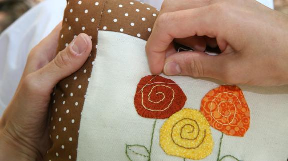 A patchwork cushion with hand stitched applique.