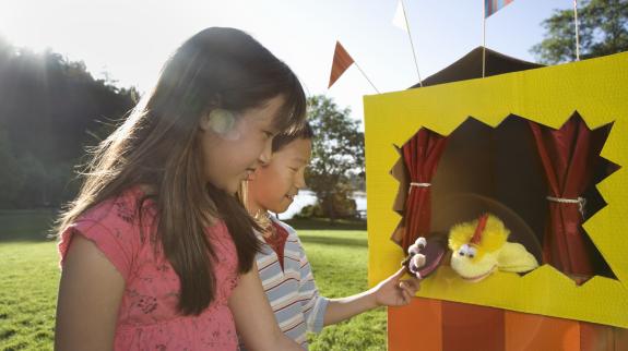 Two friends investigating puppet theater in park.