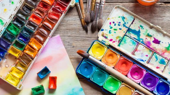 Set of watercolor paints, brushes for painting and paper sheet of painting on old wooden background. 