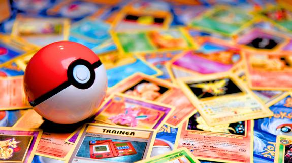 A poké ball sits on top of some Pokémon cards.