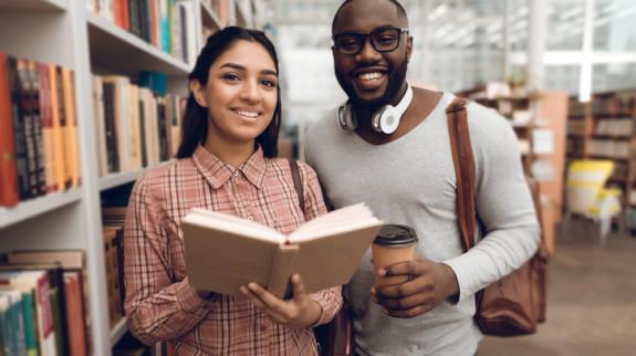 A young woman and a young man are looking for books in a library.
