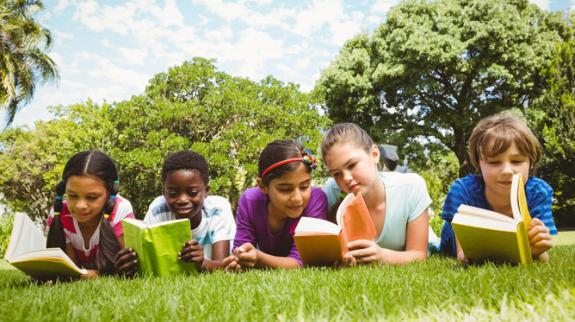 Kids on grass reading books.