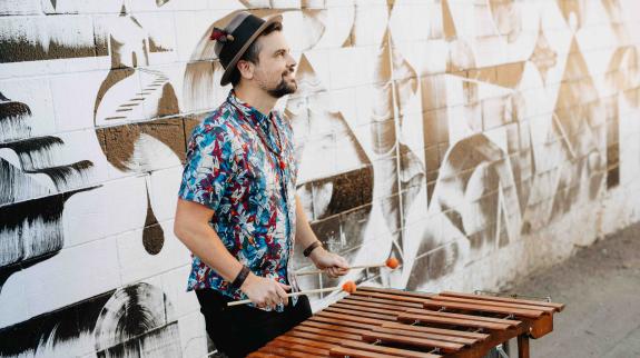 Robin Layne playing the marimba in front of a street mural.