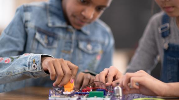 Two tweens work together to learn coding using a Snap Circuit board.