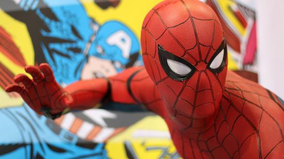 A person dressed as Spider-man in front of a mural of Captain America.