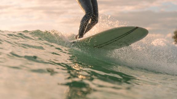 A person skillfully rides a surfboard atop a large, crashing wave in a vibrant ocean setting.
