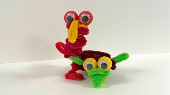 red and green pipe cleaner formed to make a critter with eyes