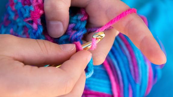 Close up of hands crocheting a blanket.