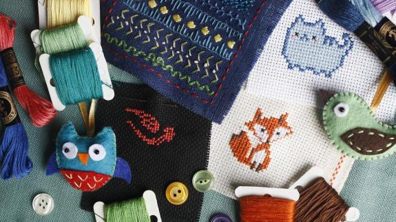 A collection of colorful cross stitch kits and spools of thread arranged neatly on a table.