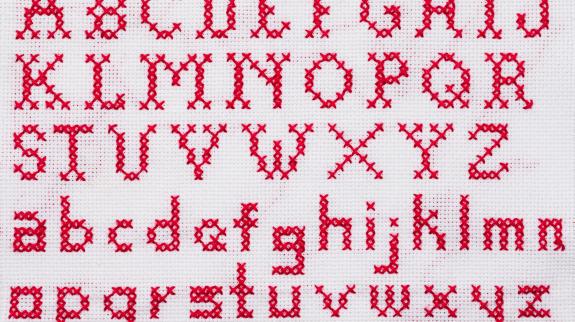 Red Alphabet cross stitch sampler with upper case and lower case letters.