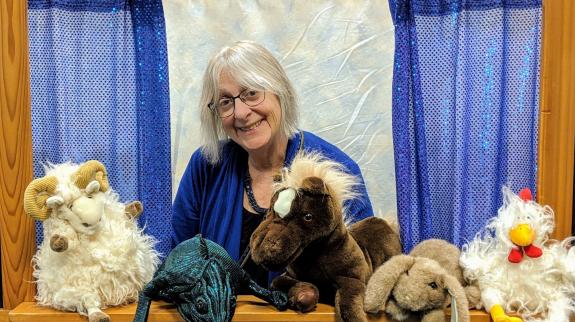 Puppeteer, and master storyteller, Elspeth Bowers poses on a stage with her puppets.