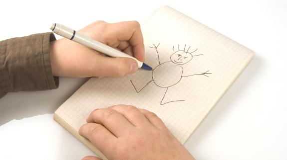 A pair of hands draw a funny stick person on graphing paper.