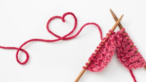 Incomplete heart knitting project with wooden needles