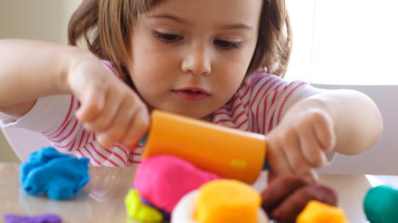 Little girl creating with playdough.