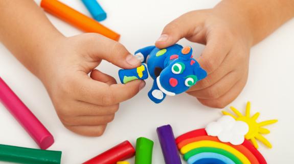 Child playing with colorful clay making animal figures - closeup on hands.
