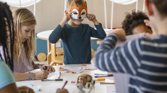 Children having a creative art face mask workshop in a library.
