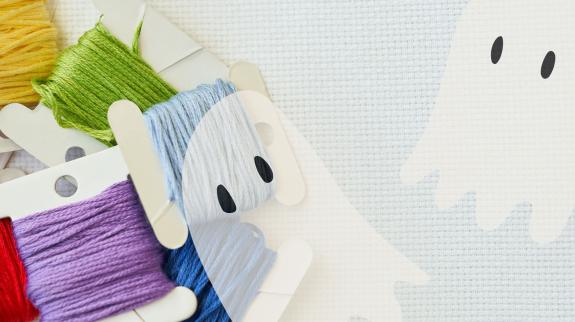 embroidery floss on aida cloth background with two almost transparent ghosts