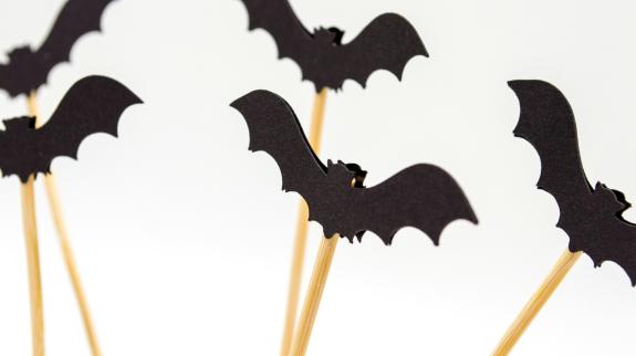 Black bat puppets made from paper and wood sticks. 