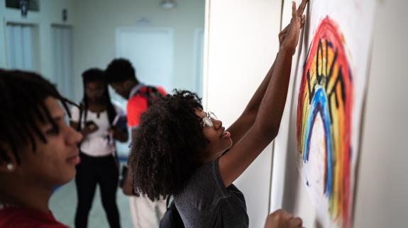 Students taping hand-painted poster to wall.