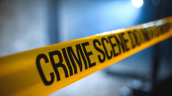 Crime scene barricade tape unrolled blocking a scene. 