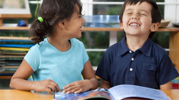 Two delighted kids enjoying a book in a library.