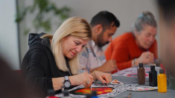 A group of multi-racial people with different ages are joining an art painting therapy session class.