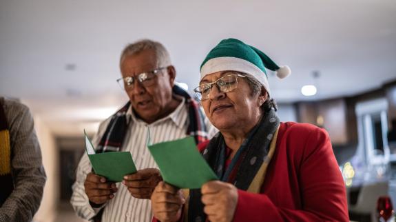 Senior couple singing together at library's Christmas event.