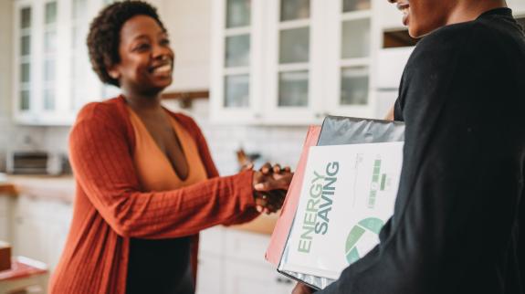 A green sustainable energy advisor is shaking hand with a customer at home.
