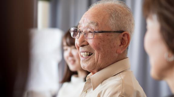 A senior Asian man participates in a conversation circle at the library.