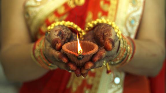 Indian woman holding Diwali oil lamp.