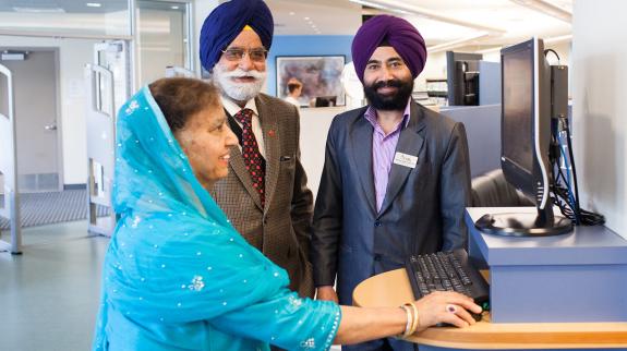 An FVRL staff member helps a Punjabi couple at Muriel Arnason Library.